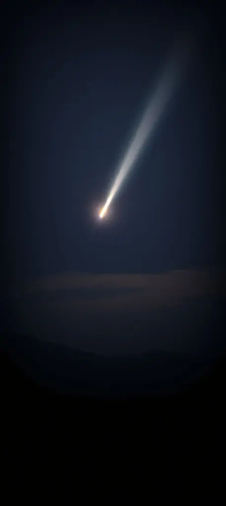 Comet trail in night sky with atmospheric haze and soft lighting.