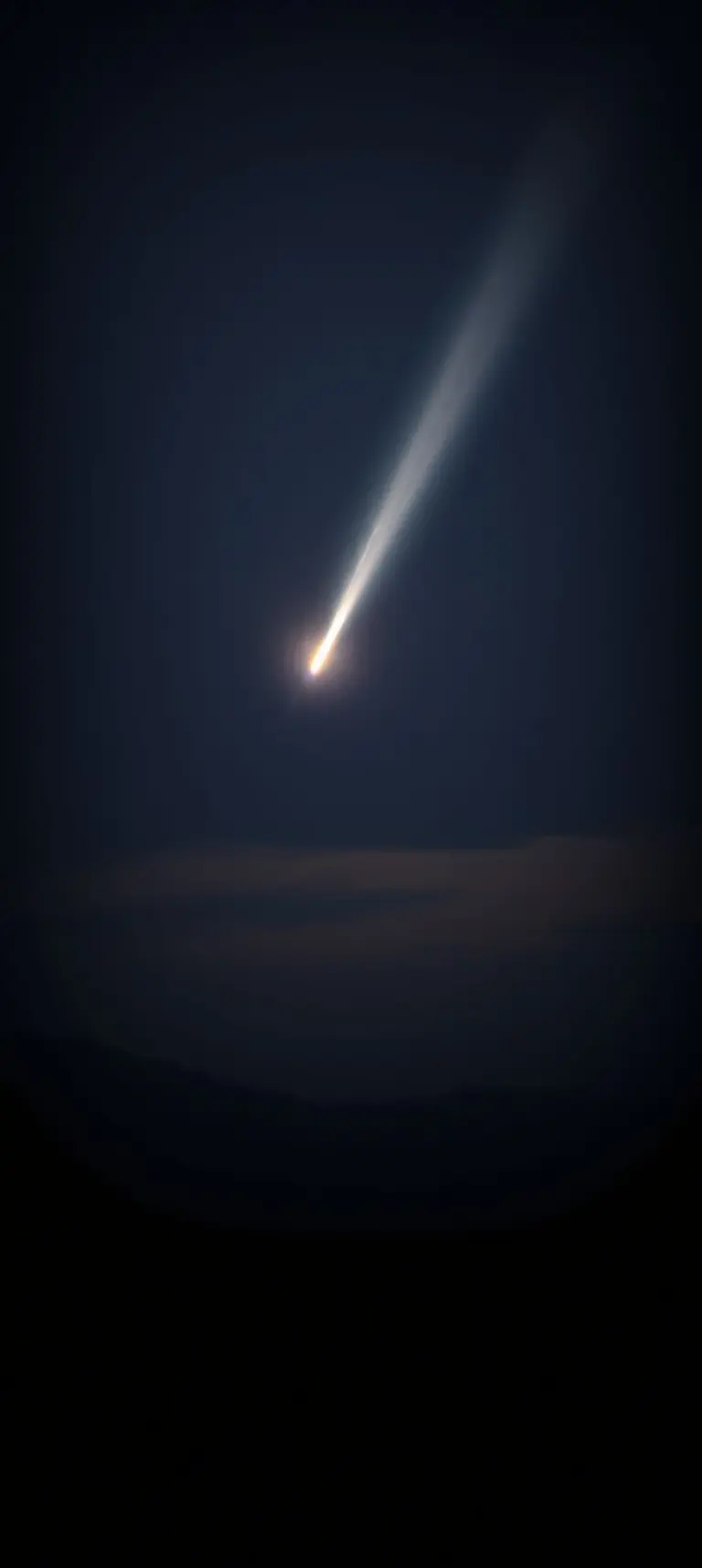 Comet trail in night sky with atmospheric haze and soft lighting.