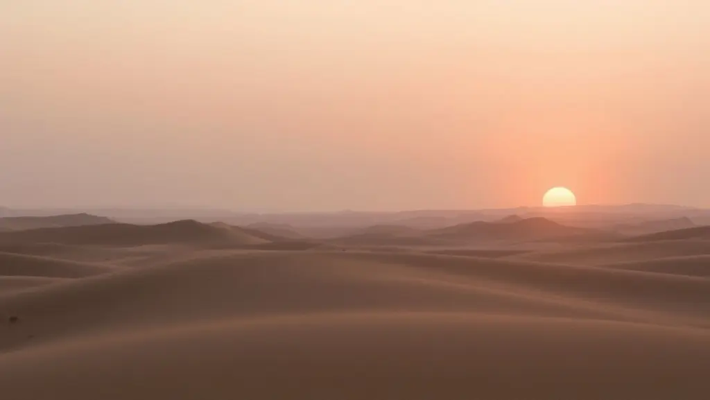 Sunrise over a desert landscape with pastel colors and soft light.