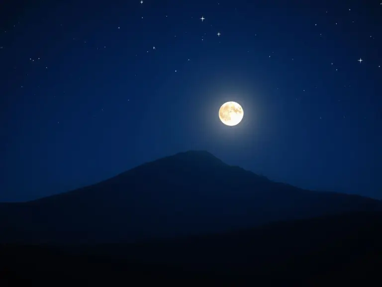 Dzhangitau Mountain silhouette against a blue, star-filled night sky with moonlight.