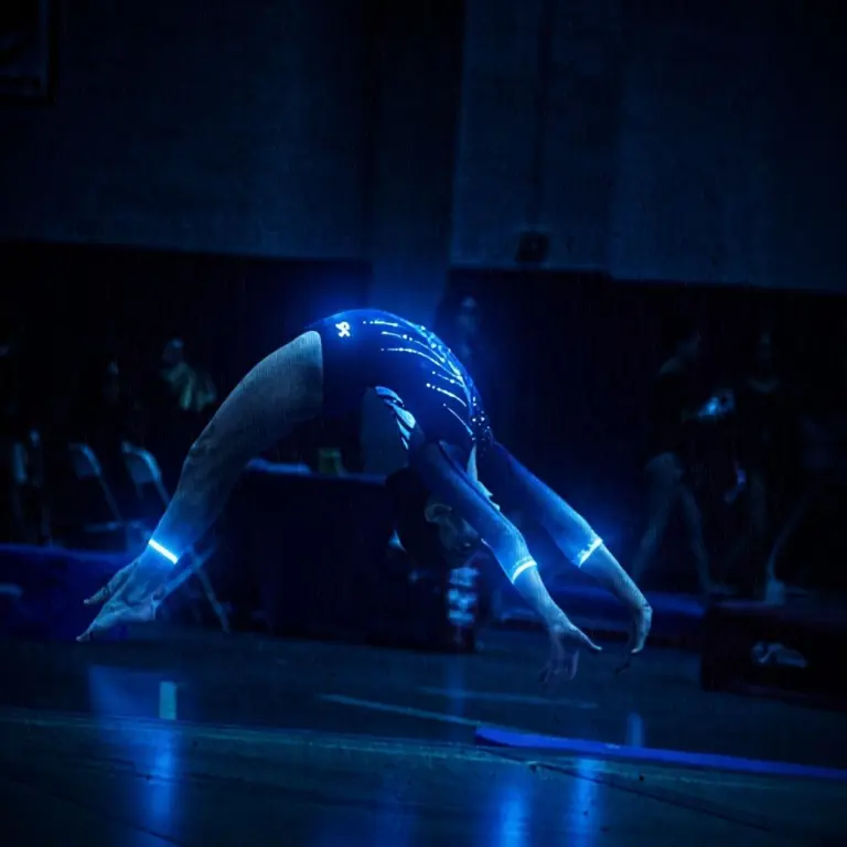Person in a glowing blue leotard during a rainstorm at night.