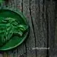 Green wax seal with wolf profile on tree bark.