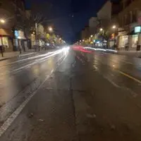 Blurry street at night with glowing car lights.