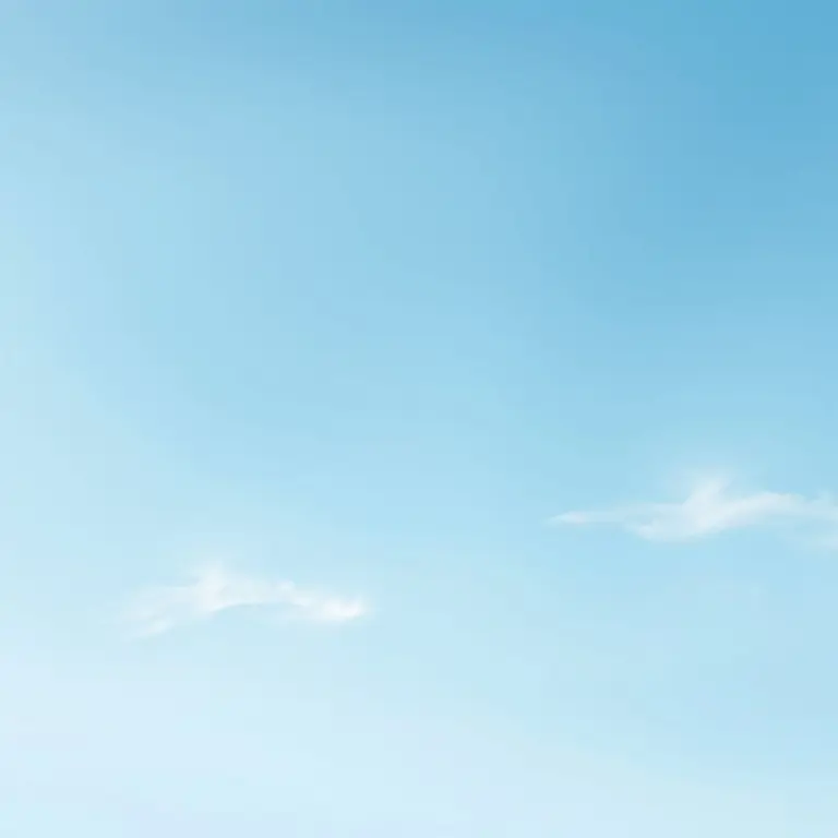 Pale blue sky with soft gradient and wispy clouds.