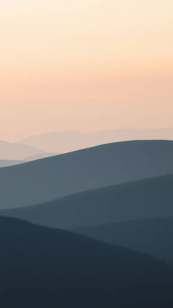 Rolling hills at dawn with pastel sky and mist.